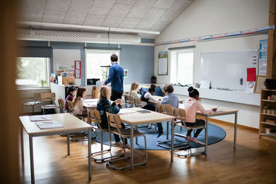 Male teacher teaching students in classroom at school