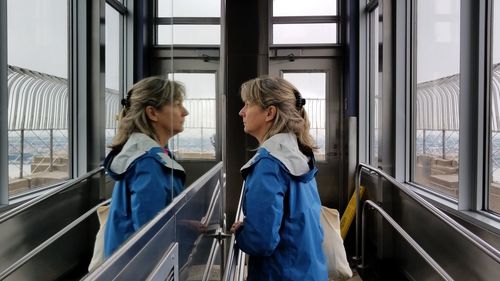 Side view of mature woman reflecting on glass