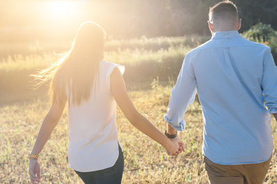 Rear view of couple kissing on field