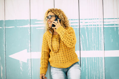 Woman holding yellow while standing against wall