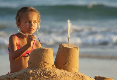 Girl making sandcastle at beach during sunset