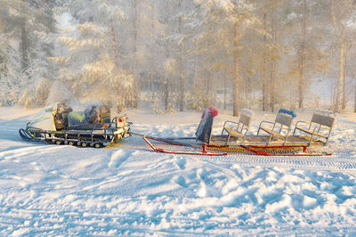 Snowmobile with sleigh in the winter forest. view from the side.