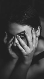 Close-up portrait of woman covering face with hand