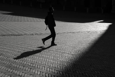 Side view of man walking on cobblestone street