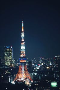 Illuminated tokyo tower amidst buildings in city at night