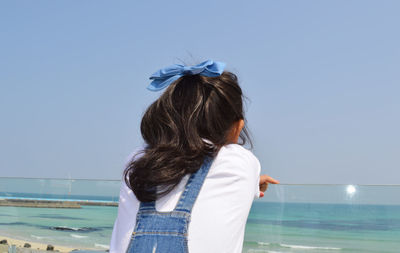 Little girl with curl ponytail hair overlooking to the ocean in jeju island, south korea