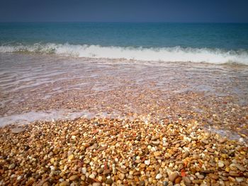 Pebbles on coastline against sky