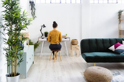 Young woman working while sitting on stool at home office