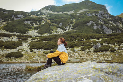 Woman sitting on rock by mountains