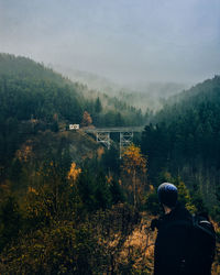 Rear view of man standing on mountain against sky
