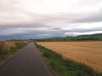 Road amidst agricultural field against sky