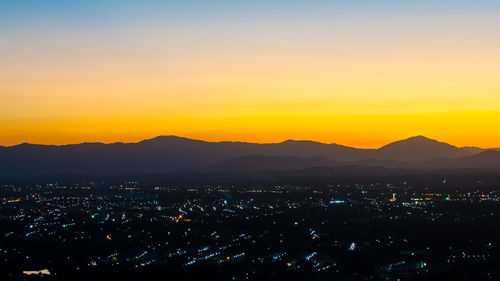 Illuminated cityscape against sky at sunset