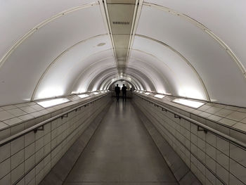 Rear view of men walking at illuminated underground walkway