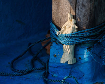 Close-up of virgin mary tied on wooden post in boat