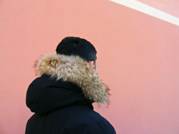 Man wearing fur coat against wall during winter