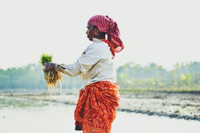 Full length of woman standing on rock against sky