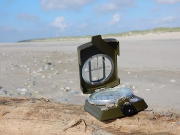 Close-up of clock on sand at beach against sky