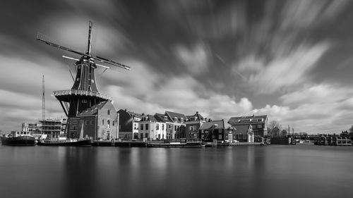 Cranes at harbor against cloudy sky