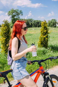 Young woman using mobile phone while sitting on field