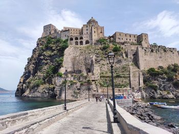 Buildings by sea against sky