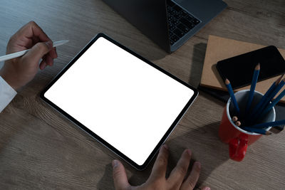 Cropped hands using digital tablet while sitting on table