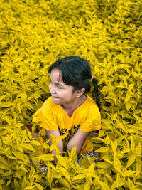 Portrait of smiling girl standing by yellow flowering plants