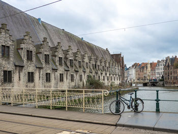Bridge over canal by buildings in city against sky