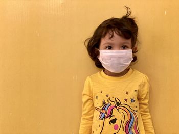 Portrait of boy standing against yellow wall