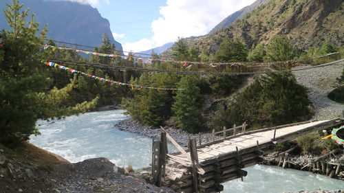 Bridge over river amidst mountains against sky