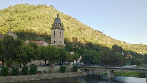 Bridge over river amidst buildings against clear sky