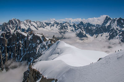 Snowy peaks and mountaineers in a sunny day at the aiguille du midi, near chamonix, france.