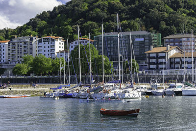 Sailboats moored in sea against buildings