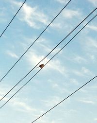 Low angle view of power cables against sky