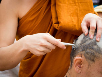 Midsection of monk shaving man head