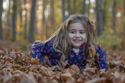 Portrait of smiling girl lying on field in forest