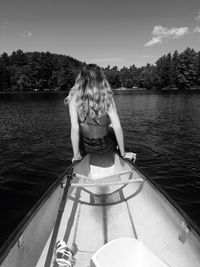 Rear view of young woman sitting on boat in lake