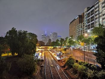 Railroad tracks amidst buildings against sky at night