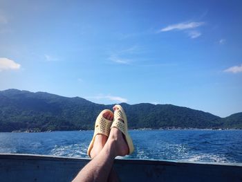 Low section of woman in sea against blue sky