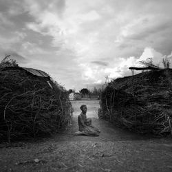 Young woman sitting against sky