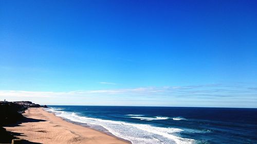 Scenic view of beach against clear blue sky