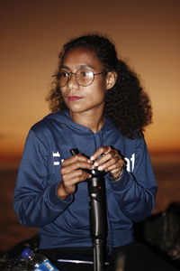 Young woman with curly hair enjoying the sunset holding gimbal stabilizer