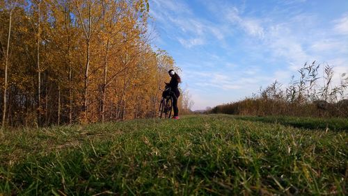 Man standing on field by trees against sky