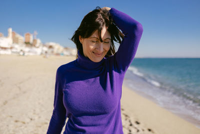 Beautiful happy mature woman enjoying a sunny winter day at the beach