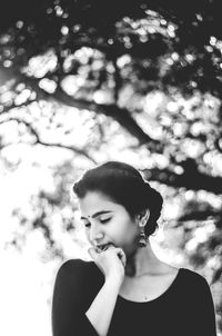 Close-up of young woman against tree