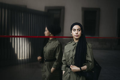 Young woman standing against wall