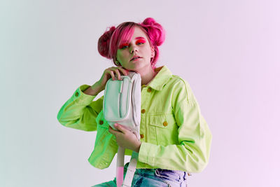 Portrait of young woman standing against white background