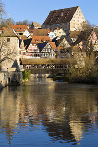 Bridge over river by houses and buildings against sky