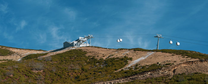 Electricity pylon by mountain against sky