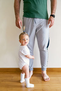 Midsection of mother with daughter standing on hardwood floor