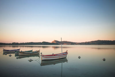 Boat moored in lake against sky during sunset